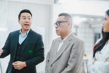 Asian businessman present start up project to expert investor, Teamwork group of multicultural business team solving problems, discussing business idea with skyscraper at modern business lounge