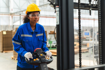 African American female worker driving forklift truck in heavy metal industrial factory, Smiling...