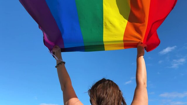 Gay pride parade, woman woman holding flag with rainbow lgbt flags