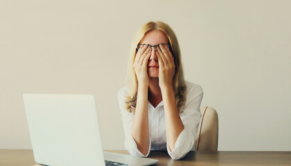 Tired overworked woman employee suffering from headache, rubbing eyes, working with laptop