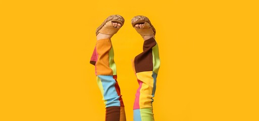 Legs of young woman in bright pants and sandals on yellow background