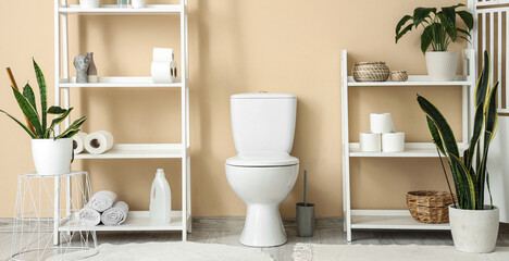Interior of restroom with toilet bowl near beige wall