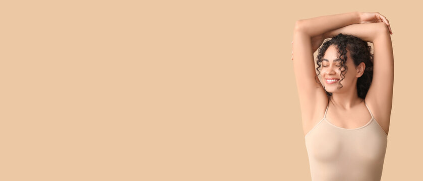 Beautiful young African-American woman on beige background with space for text. Concept of using deodorant