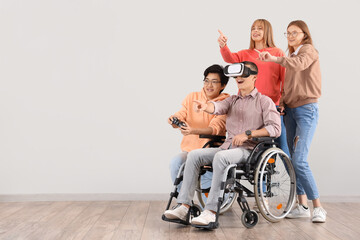 Group of teenagers with boy in wheelchair playing video game near light wall