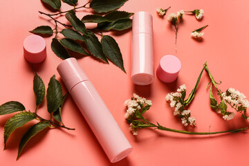 Bottles and jars of cosmetic products with beautiful flowers on red background