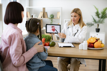 Mature experienced female doctor showing tablet with gastrointestinal tract image for treatment...