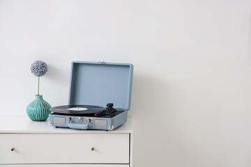 Cabinet with record player and vase near white wall