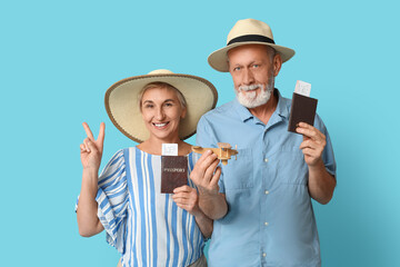 Mature couple with passports and wooden airplane on blue background. Travel concept