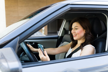 Woman smiling while using smartphone while driving, emphasizing the dangers of distracted driving