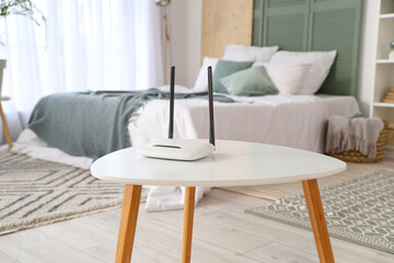 Modern wi-fi router on table in bedroom, closeup