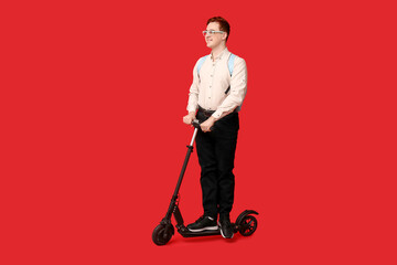 Young man riding modern electric kick scooter on red background