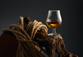 Brandy snifter and rope on a old wooden snag.