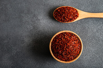 Red pepper flakes.Red chili peppers in wooden bowl on black background
