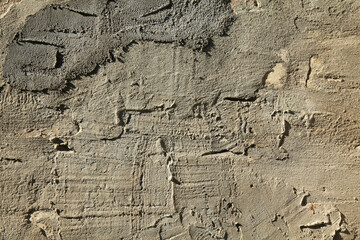 Old, sloppy, multi-layered wall covering of the house. Rough, uneven surface. Cement plaster on a brick wall, texture, background. Ancient backdrop of yellowed color. Contrasting view of wall cladding