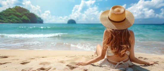 Woman in straw hat sitting on beach - Powered by Adobe