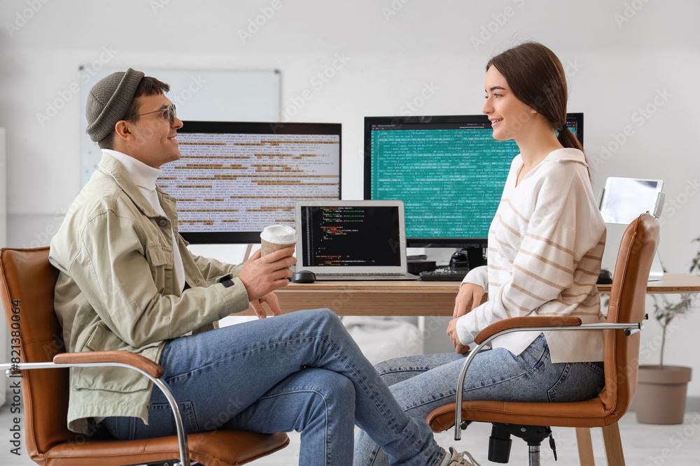 Poster couple of programmers with coffee working at table in office