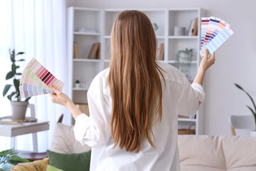 Young woman with paint color palettes at home, back view