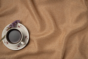 Cup of coffee with flower on fabric background from above. Vintage style. Copy space