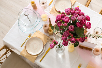 Beautiful table setting with pink roses and candles for wedding celebration in room, top view