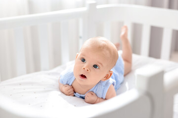 Cute little baby lying in crib at home, space for text