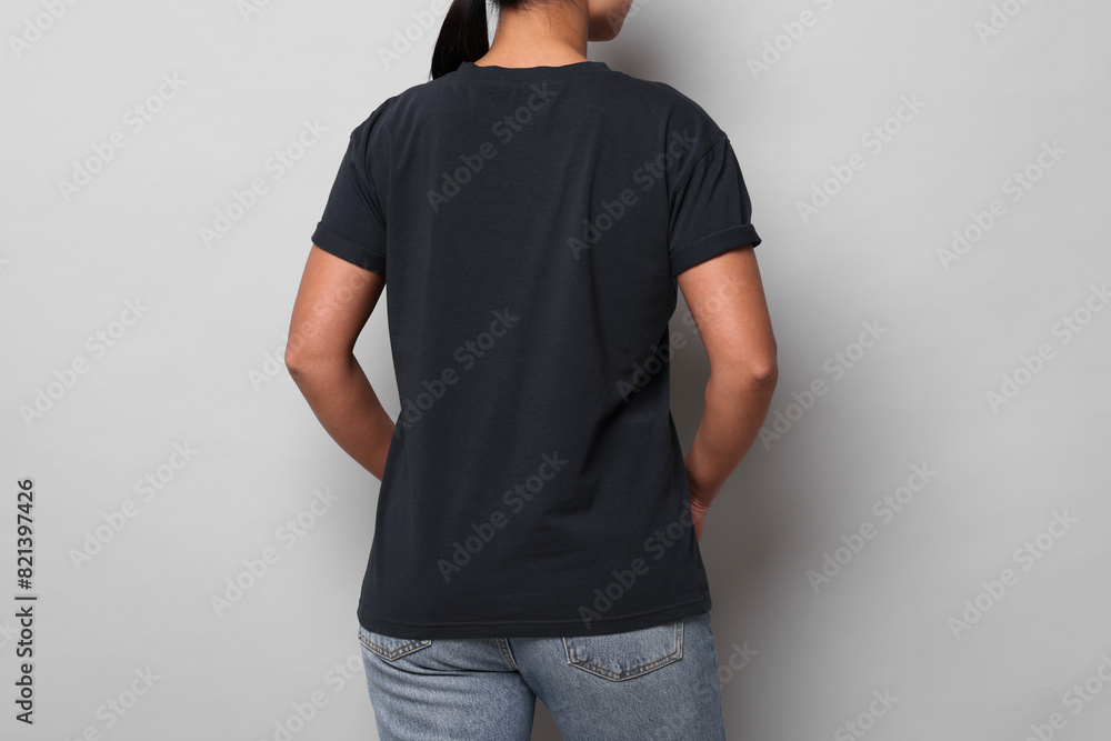 Wall mural Woman wearing black t-shirt on light grey background, closeup