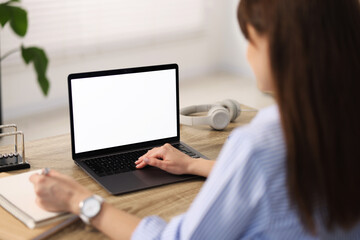 Woman taking notes during webinar at wooden table in office, selective focus