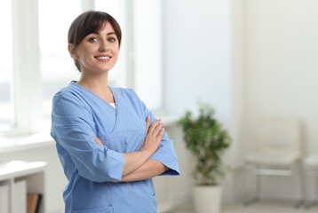 Portrait of smiling medical assistant with crossed arms in hospital. Space for text