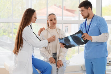 Obraz premium Doctors showing x-ray image of lungs to patient in clinic