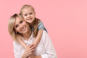 Daughter hugging her happy mother on pink background. Space for text