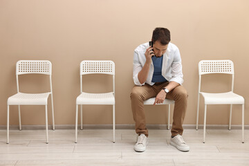 Man talking on smartphone and waiting for appointment indoors