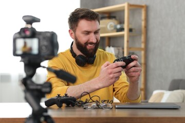 Smiling technology blogger recording video review about game controllers at home