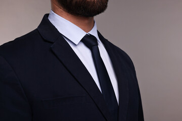 Businessman in suit and necktie on grey background, closeup