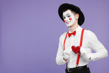 Funny mime artist with red heart on purple background. Space for text