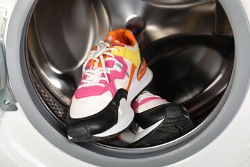 Different clean sneakers inside modern washing machine