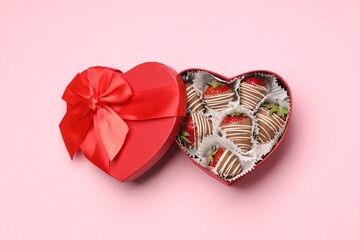 Heart shaped box with delicious chocolate covered strawberries on pink background, top view
