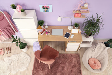 Interior of stylish teenager's room with workplace, plants and beanbag