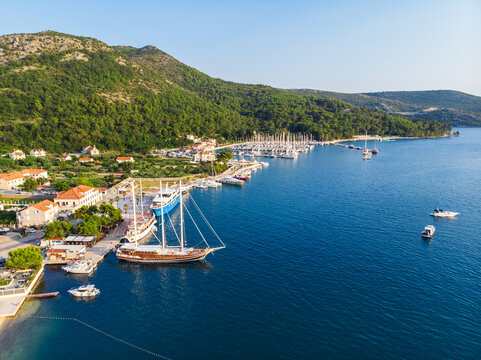 Scenic aerial view many yachts boats moored at Croatian bay harbor shore blue turquoise clear water at bright summer sunny day. Top above Mediterranean sea marina. Boat vessel charter service