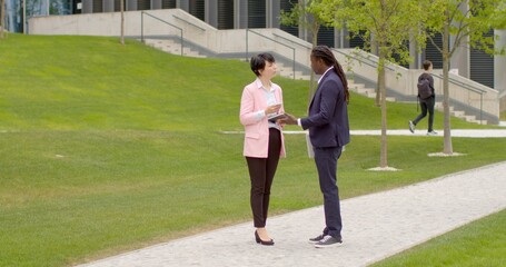 Two people talking outside. Chatting track offers more relaxed environment, encourage more open and free dialogue. People are standing on the street at summer. Man with woman talking outdoor.