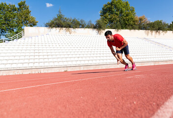 Fototapeta premium Stadium, man running and start block of athlete on a runner and arena track for sprint