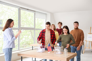 Fototapeta premium Voting young people with USA flag near ballot boxes at polling station
