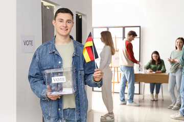 Voting young man with ballot box and German flag at polling station