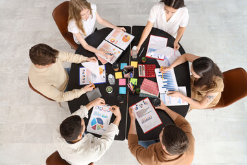 Group of business people with diagrams working on marketing plan at table in office, top view