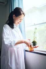 苔玉に霧吹きをかけるシニア女性