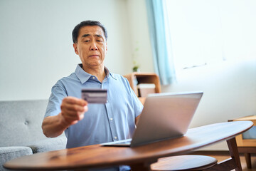 ネットショッピングでクレジットカード番号を打ち込むシニア男性