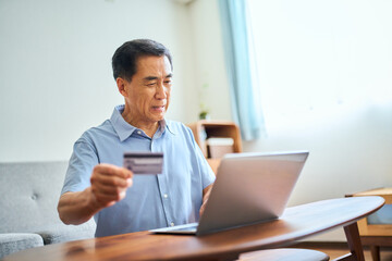 ネットショッピングでクレジットカード番号を打ち込むシニア男性
