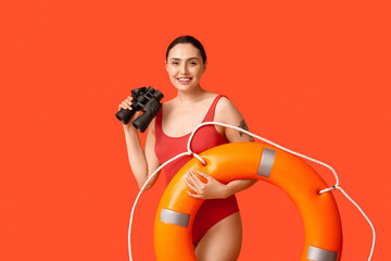 Female lifeguard with ring buoy and binoculars on orange background