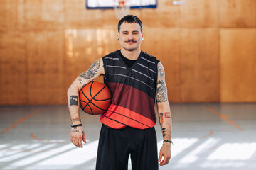 Portrait of confident smiling tattooed hispanic man basketball player