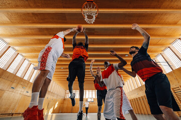 Low angle view of a multiracial men playing basketball under the hoop indoor