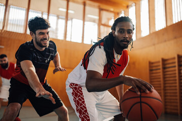 Two diverse male basketball players dribbling the ball while playing the game