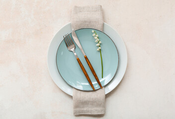 Beautiful table setting with plates, napkin, cutlery and flowers on light background